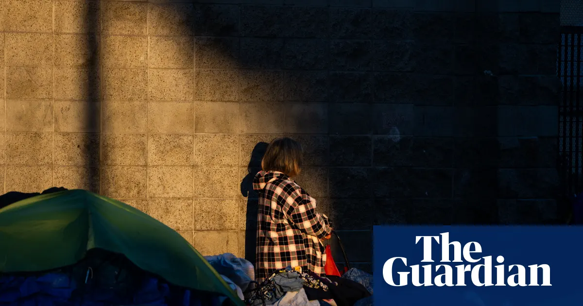 Zdjęcie przedstawiające ludzi i namioty na chodniku w Los Angeles, symbolizujące problem bezdomności.