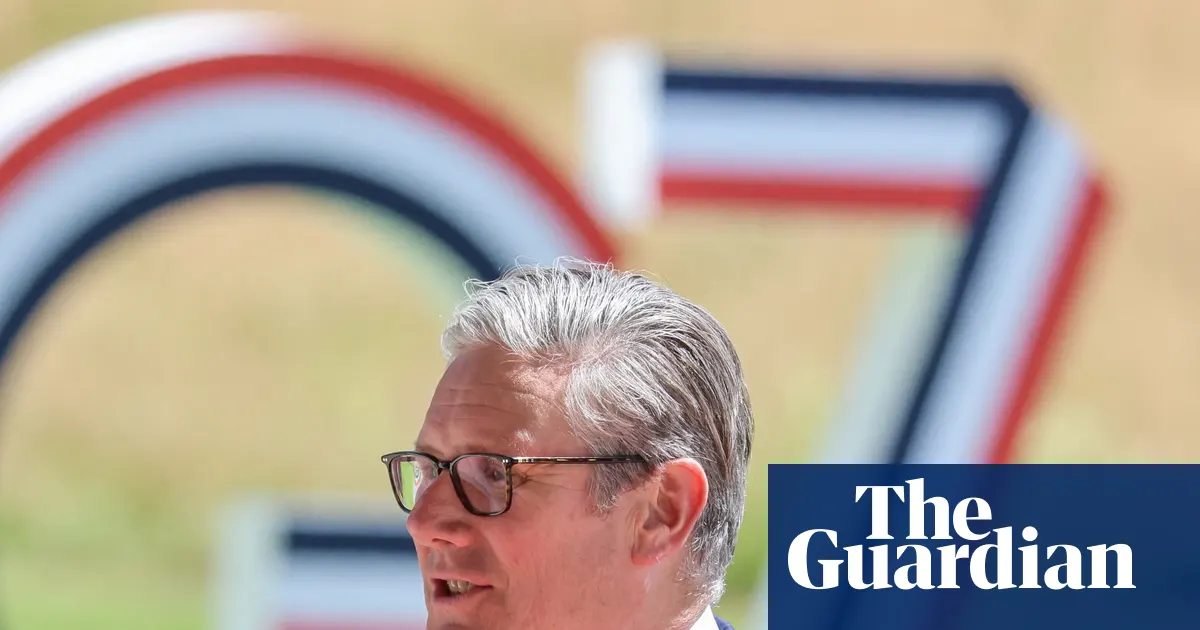 Brytyjski premier Keir Starmer podczas szczytu G7 we Francji, w tle flagi państw uczestniczących.