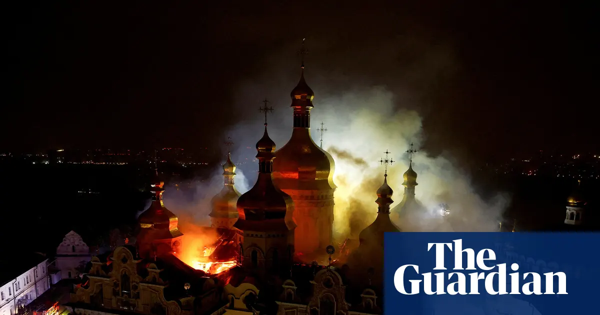 Zdjęcie przedstawiające płonącą Katedrę Zaśnięcia NMP w Ławrze Peczerskiej w Kijowie, z widocznymi wysokimi płomieniami i dymem unoszącym się w nocnym niebie.