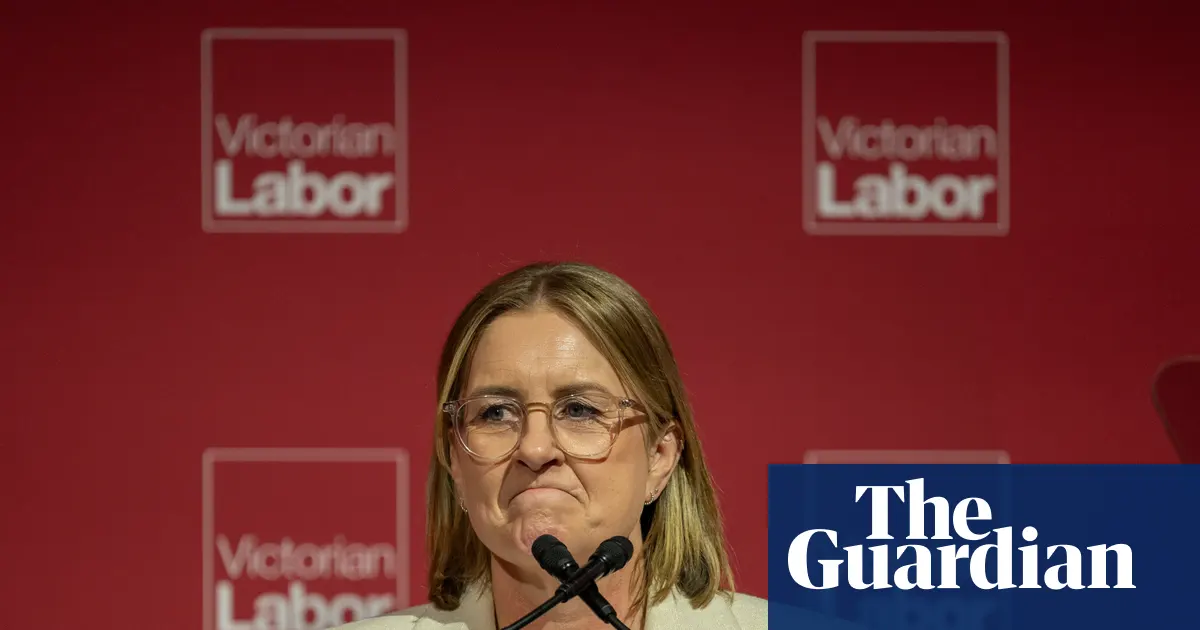 Premier Jacinta Allan przemawiająca na tle flagi stanu Wiktoria i Australii, w parlamencie.