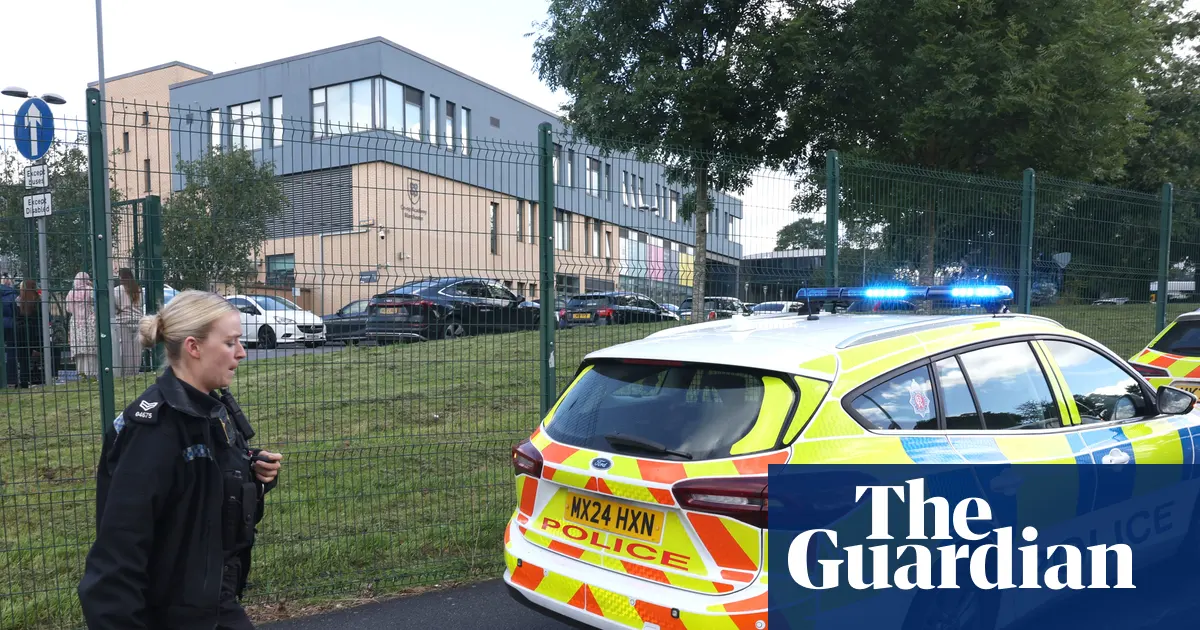 Zdjęcie przedstawia szkołę Co-op Academy w Blackley w Manchesterze, otoczoną przez służby ratunkowe po incydencie.