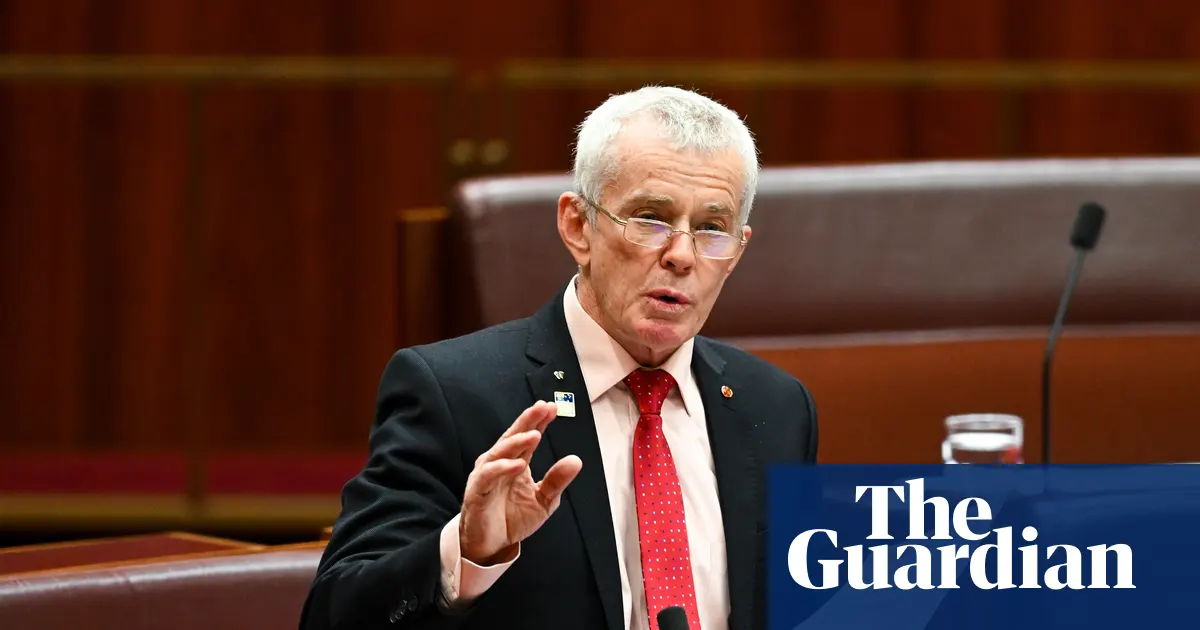 Senator Malcolm Roberts podczas konferencji prasowej, skupiony na wypowiedzi.