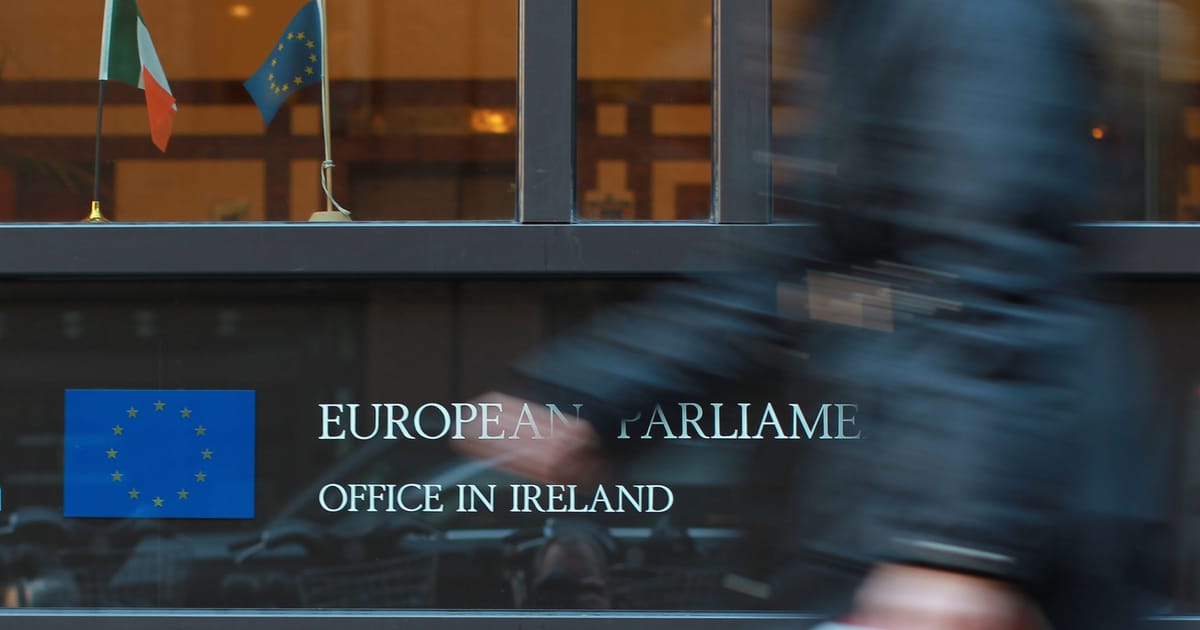 Flaga Irlandii powiewająca przed budynkiem instytucji Unii Europejskiej, symbolizująca nadchodzącą prezydencję.