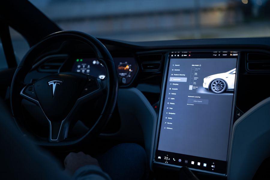 Samochód elektryczny podłączony do stacji ładowania, z ekranem pokazującym proces wymiany danych.