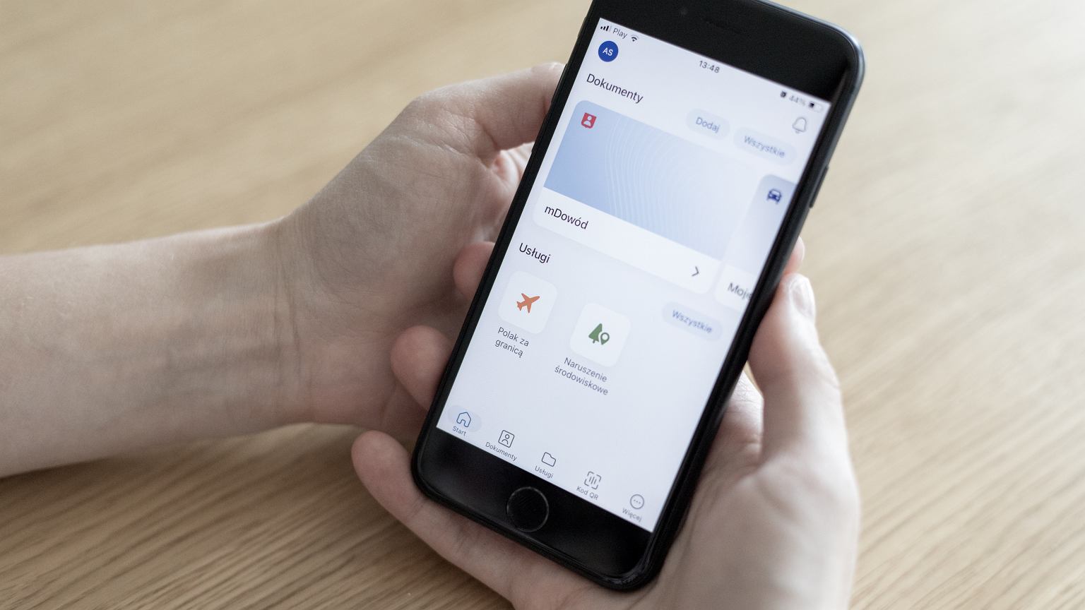 Rodzic korzystający z aplikacji mObywatel na smartfonie, składający wniosek o paszport dla dziecka