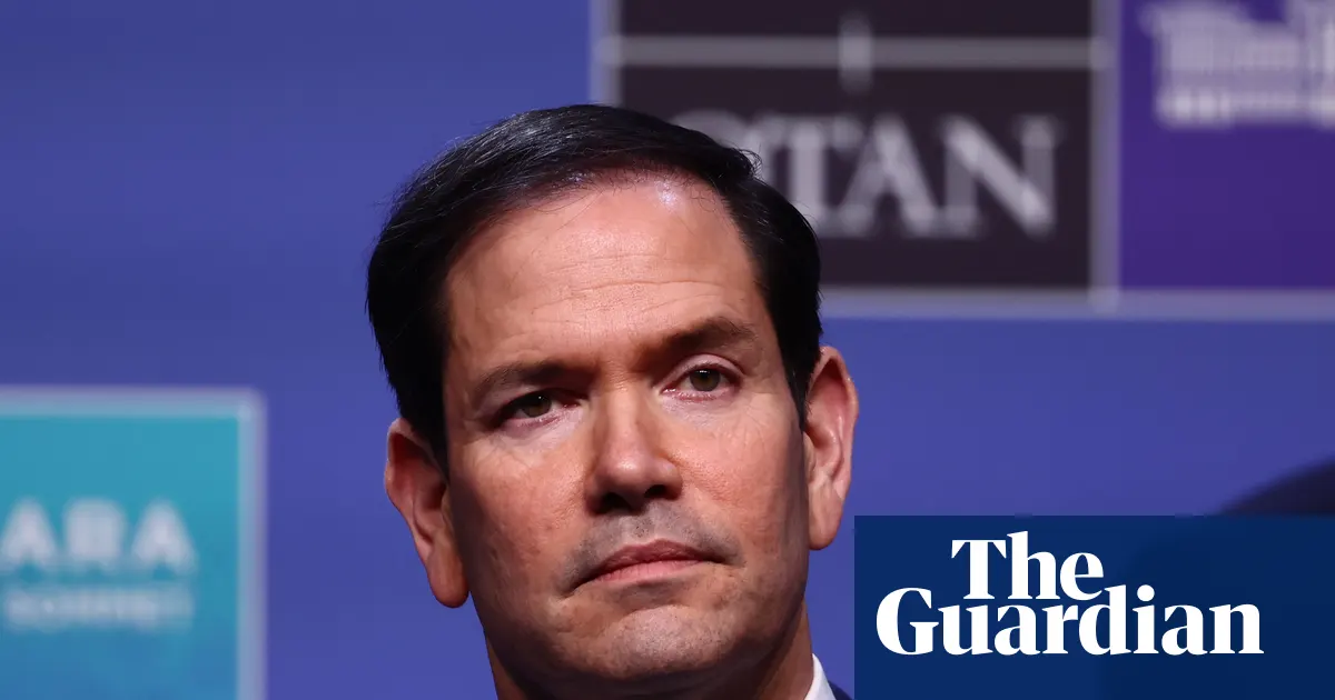 Marco Rubio, Sekretarz Stanu USA, przemawia do dziennikarzy na tle flagi amerykańskiej.