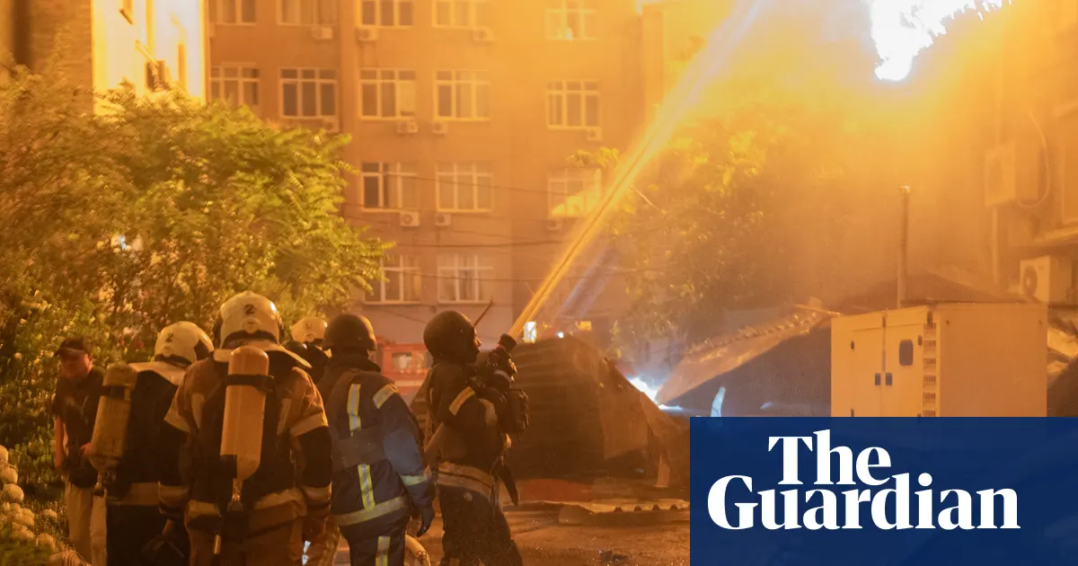 Zdjęcie przedstawiające płonący budynek w Kijowie po rosyjskim ataku rakietowym, z widocznymi służbami ratunkowymi.