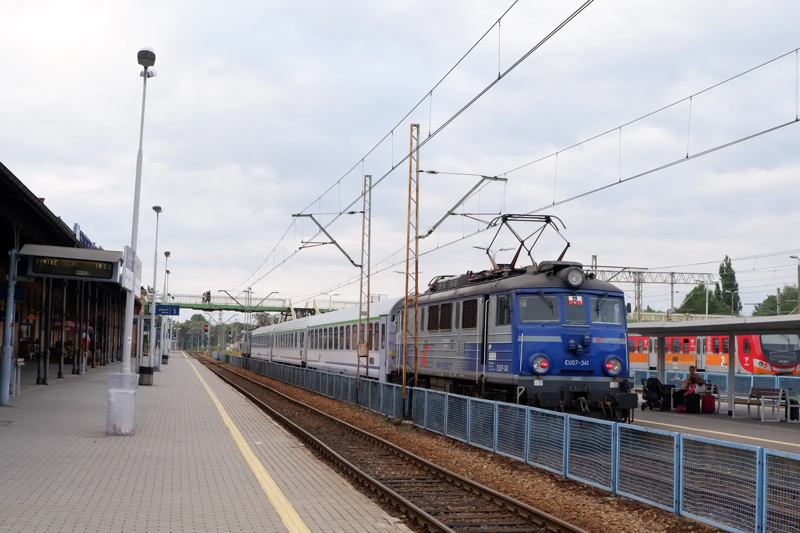 Pociąg Intercity wykolejony na torach w Trzebini, w tle karetki pogotowia i straż pożarna.