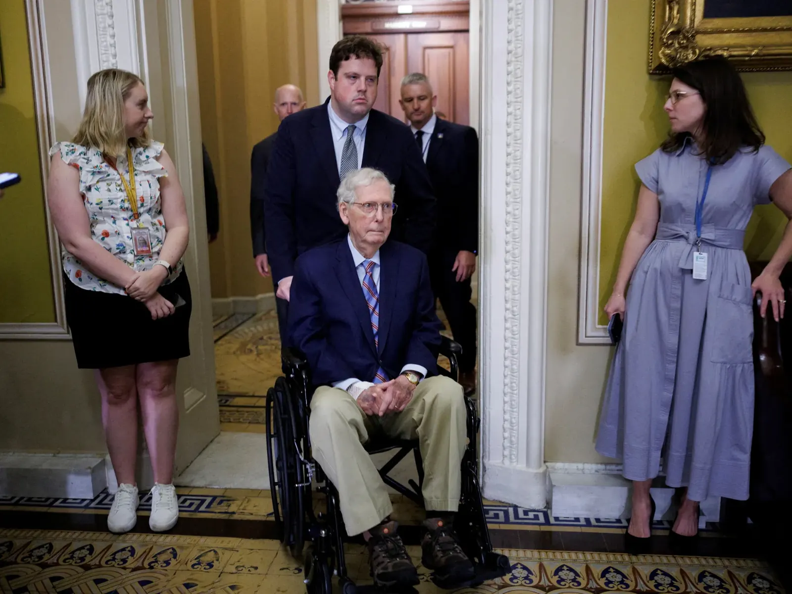 Senator Mitch McConnell uśmiecha się obok swojej żony Elaine Chao, trzymając w ręku oświadczenie.