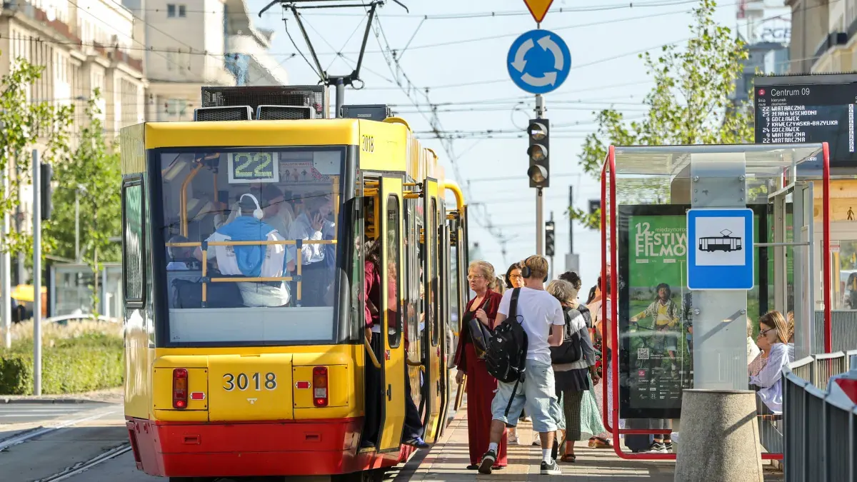 Pasażerowie wsiadający do tramwaju w Warszawie podczas Dnia bez Samochodu, na przystanku widoczna informacja o darmowych przejazdach