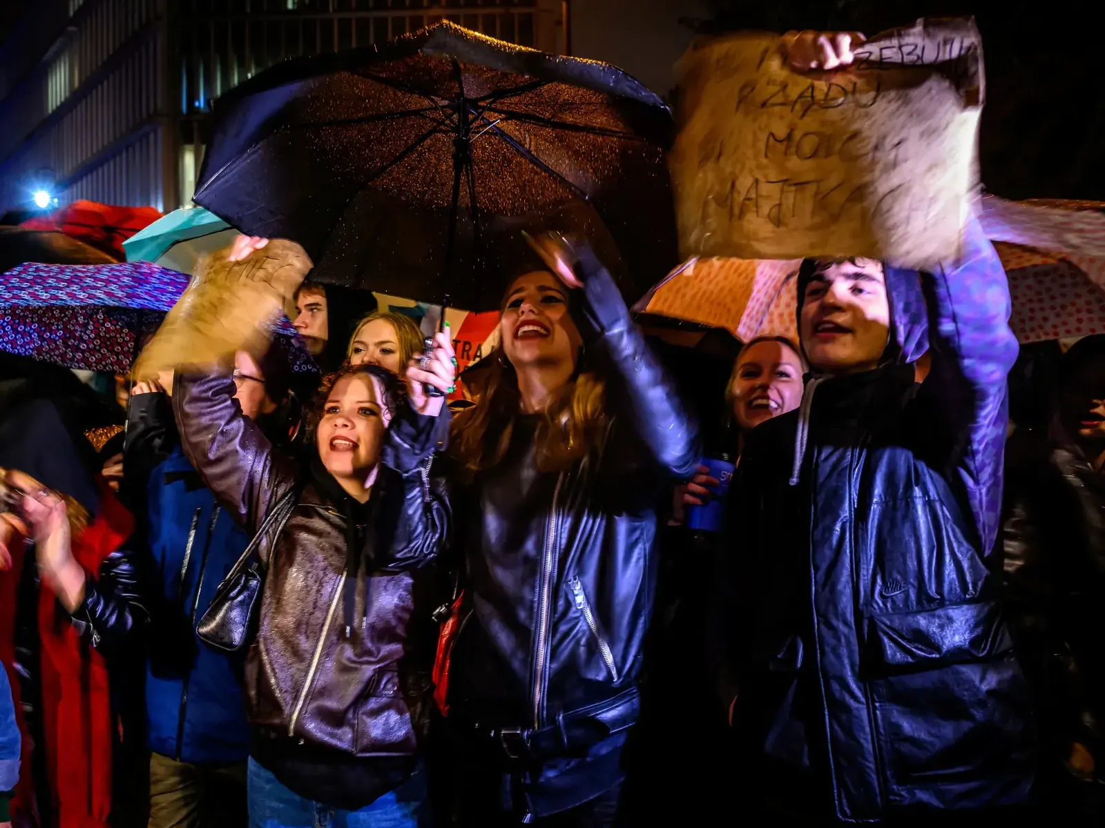 Protestujący z transparentami przed polskim parlamentem w Warszawie podczas deszczu, demonstracja w obronie praw kobiet